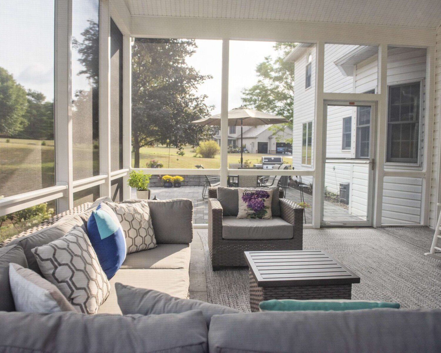 A screened in porch with couches and a mini table for resting drinks
